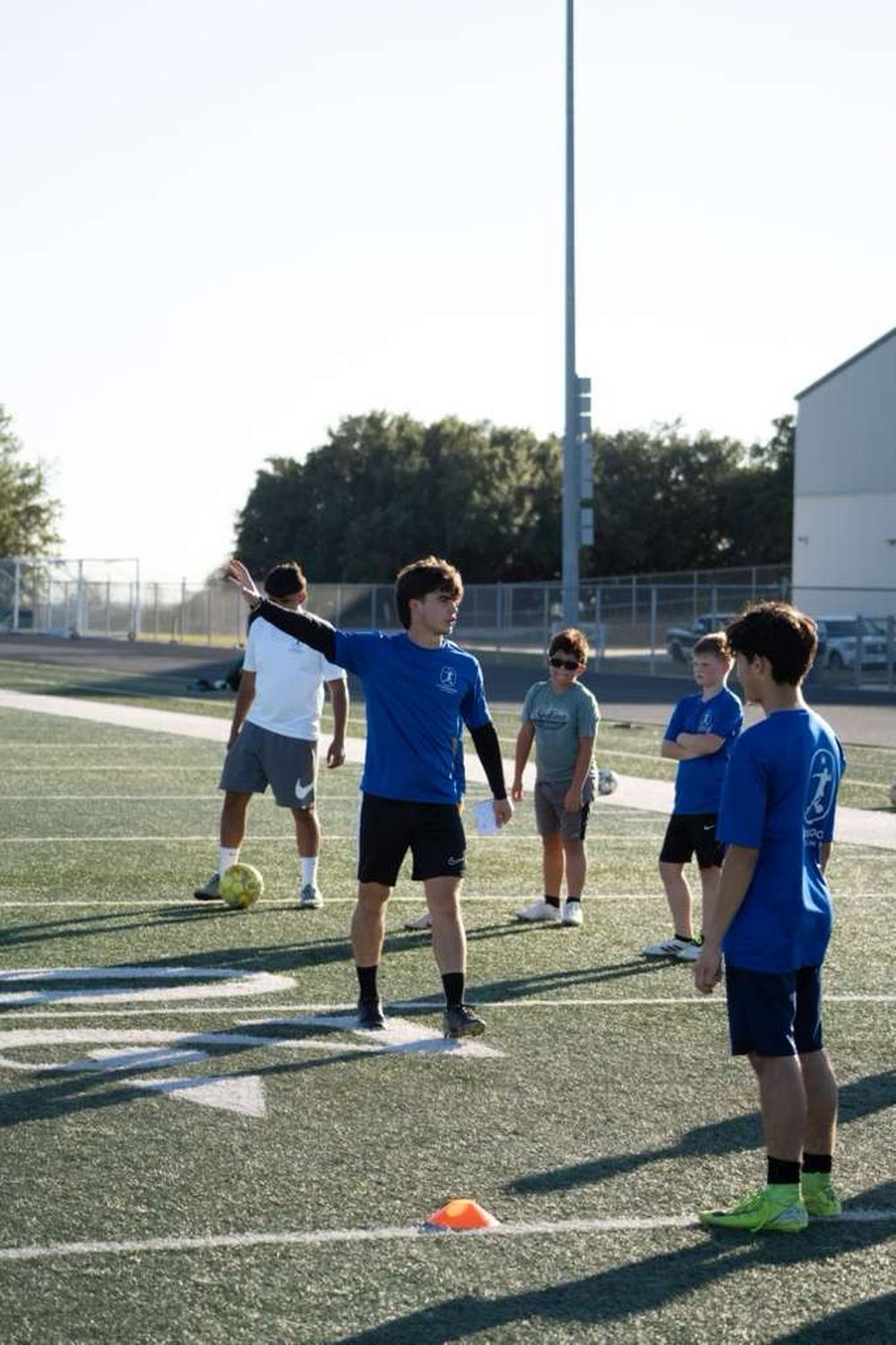 Coach Jose in a blue shirt explaining an exercise to a small group